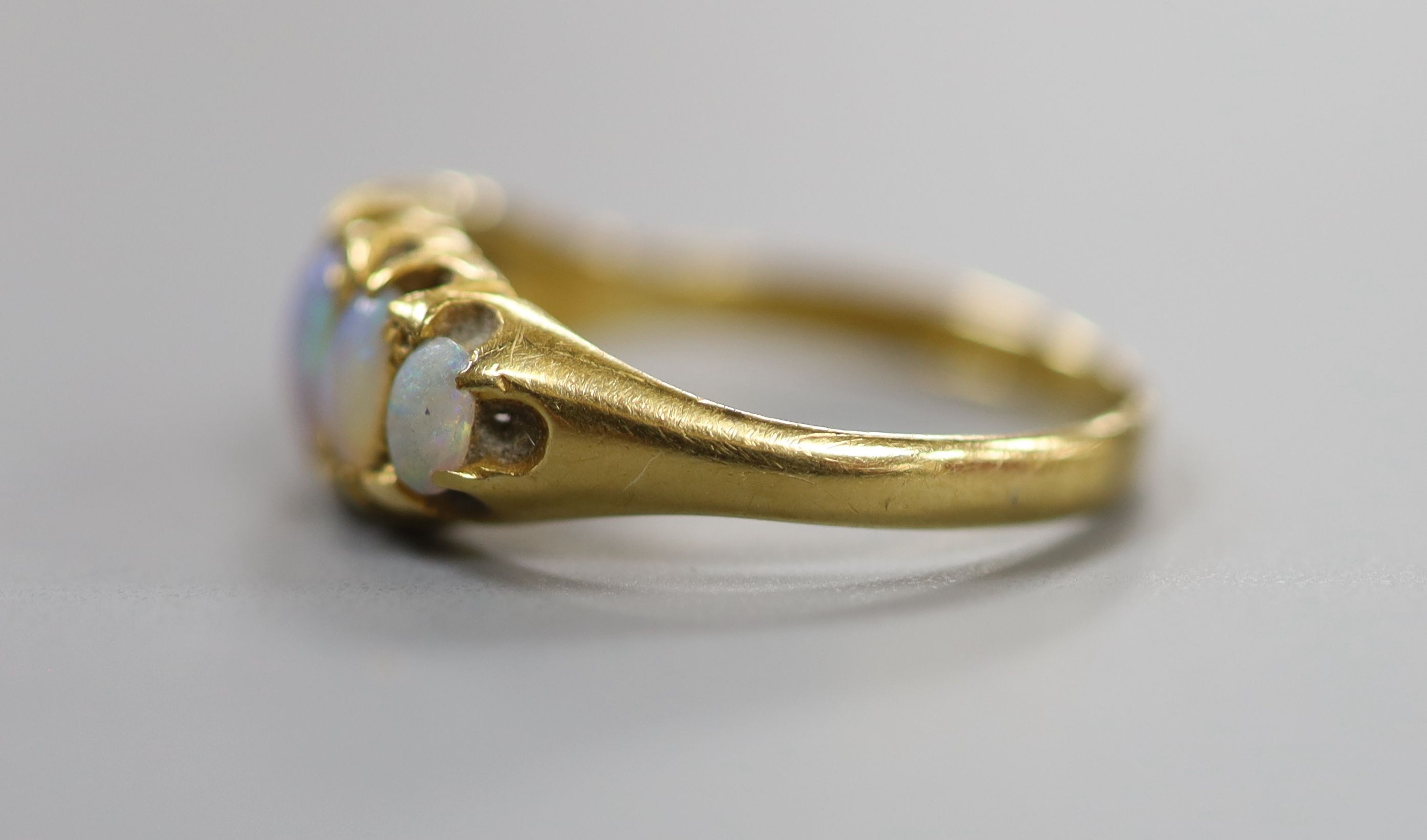 An 18ct gold and graduated oval white opal set half hoop ring, size Q/R, gross weight 3.4 grams.